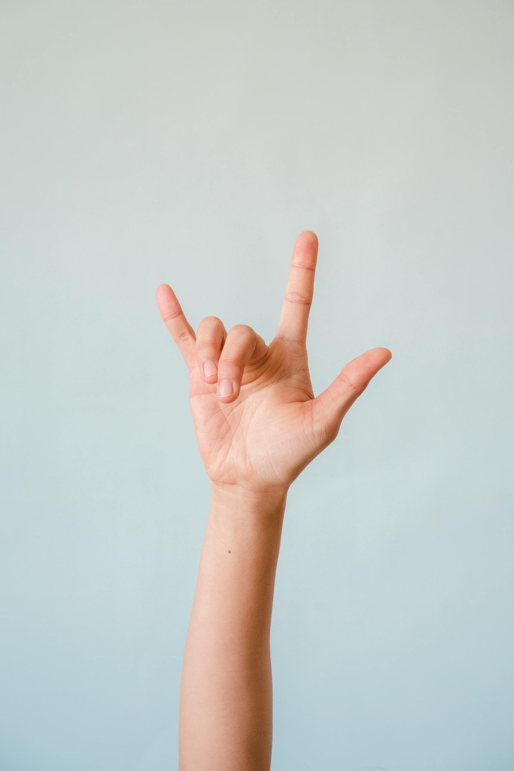 Close-up of "I Love You" hand gesture in American Sign Language against a white background.